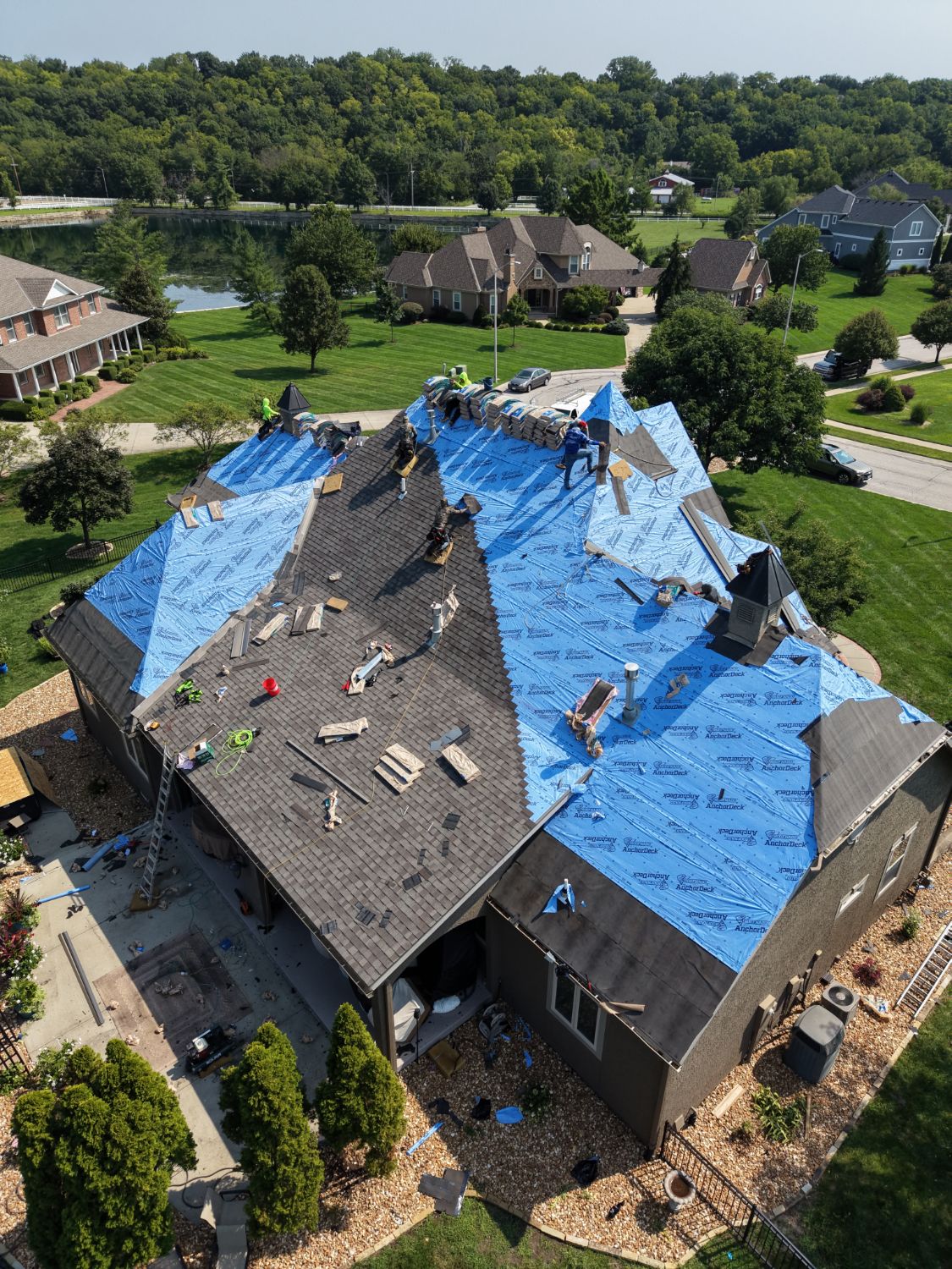 Aerial view of the AGR Roofing crew mid tear off, installing blue underlayment on a Kansas City home.